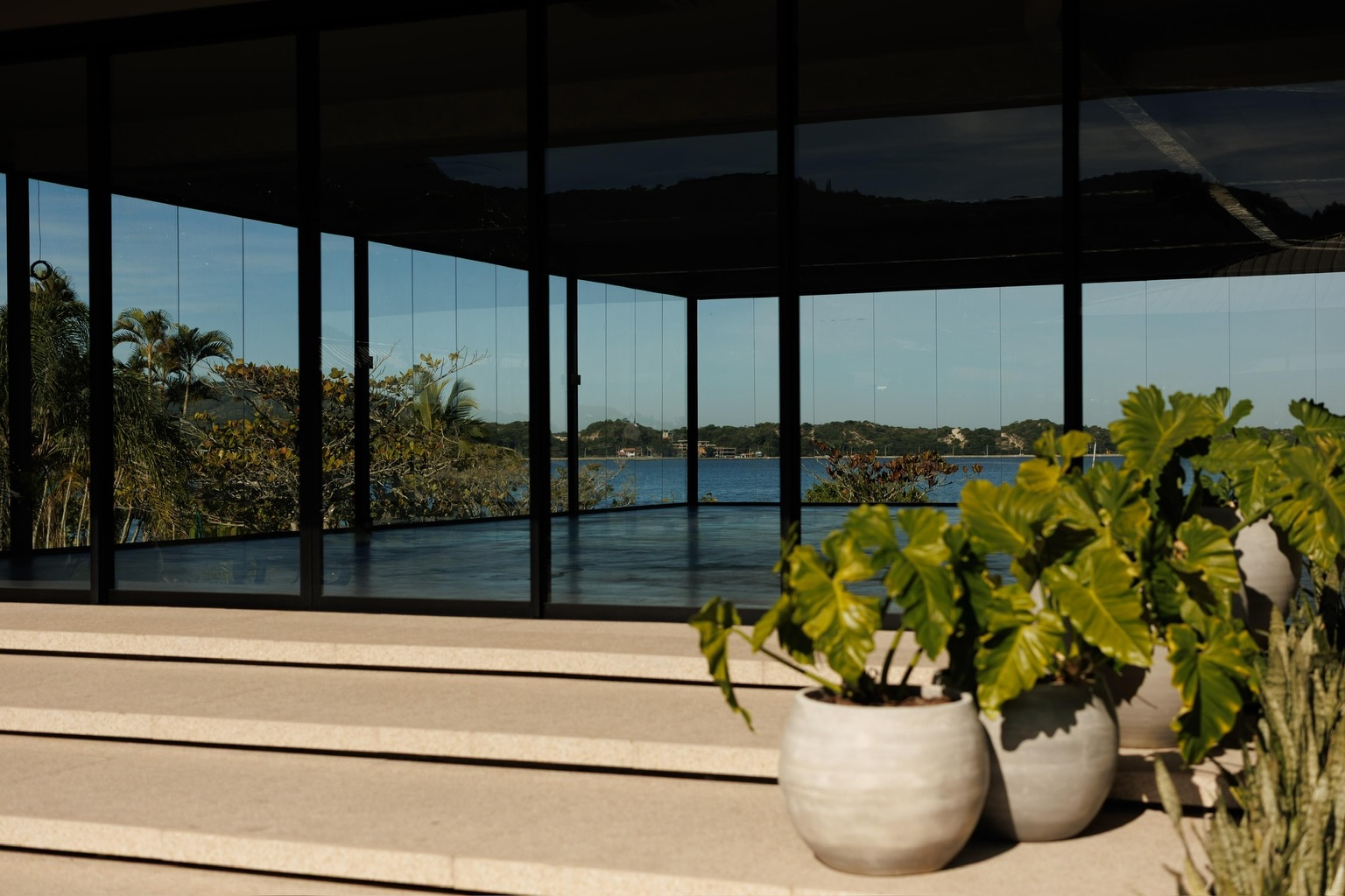 Vista da lagoa pelas janelas do salão, com plantas